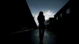 A young adult walking in a dark alleyway